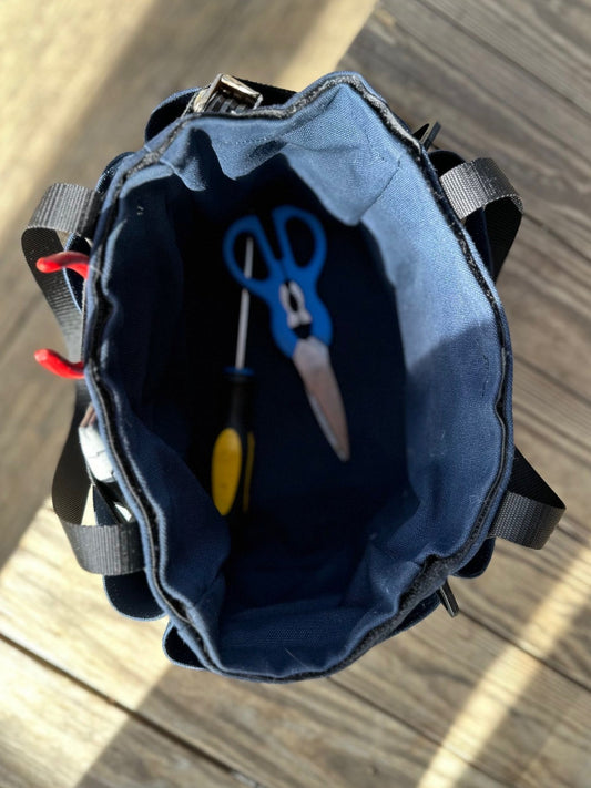 Open blue tool bag with tools inside on a wooden surface