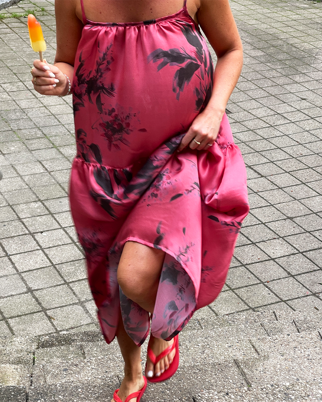 Person wearing a pink floral dress on a paved surface