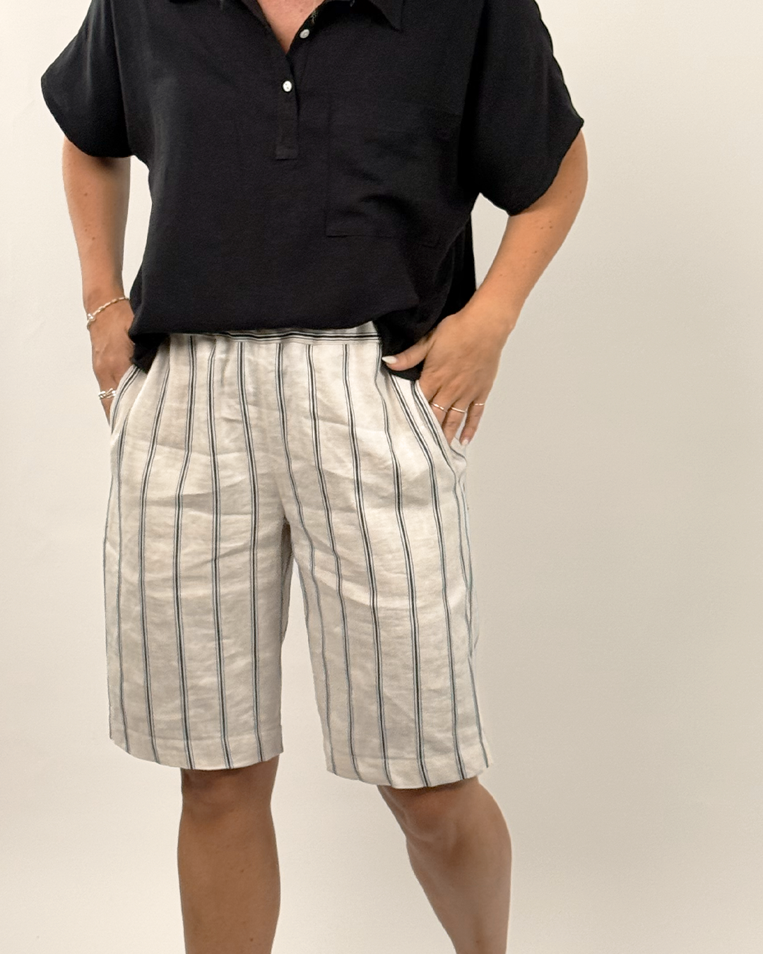 Person wearing a black shirt and striped shorts on a plain background