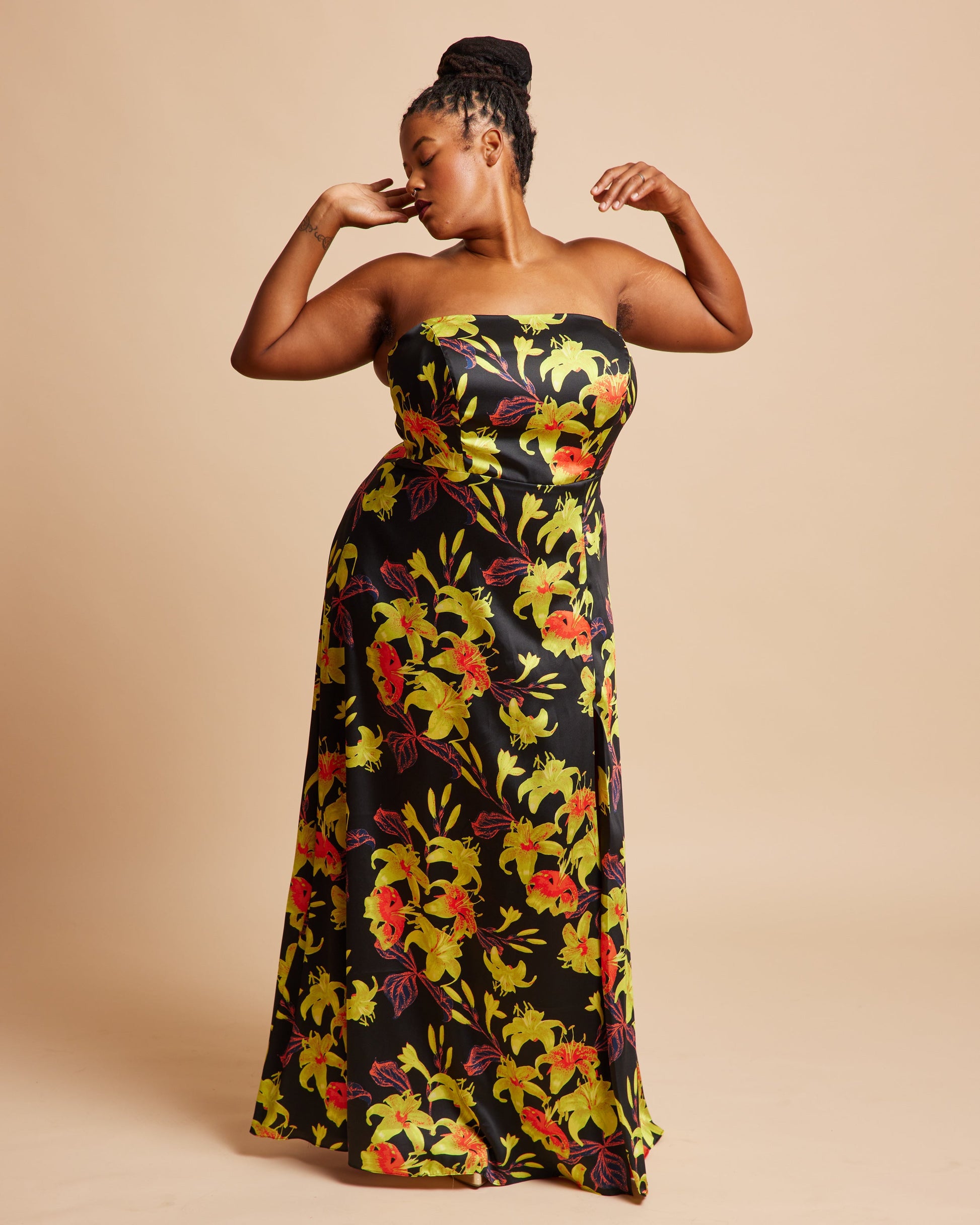Woman wearing a strapless floral dress on a beige background. This dress is the Ellington Strapless Dress sewing pattern from Cashmerette.