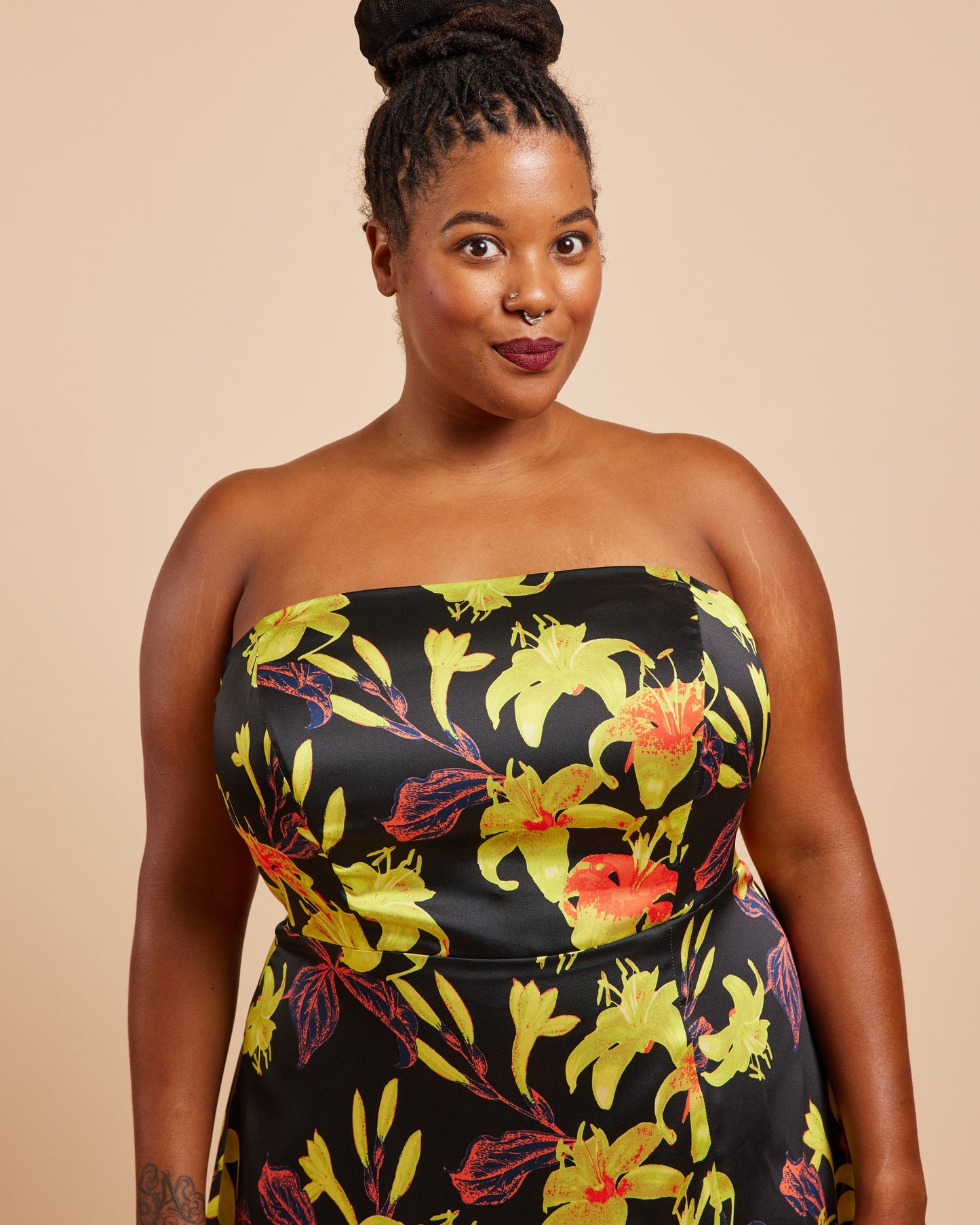 Woman wearing a strapless dress with a floral pattern on a beige background. This dress is the Ellington Strapless Dress sewing pattern from Cashmerette.