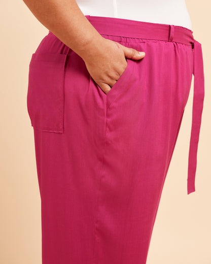 Pink pants with a belt on a beige background. These pants are the Everett Pants & Shorts sewing pattern from Cashmerette.