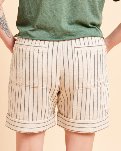 Beige shorts with black stripes worn by a person on a beige background. These shorts are the Everett Pants & Shorts sewing pattern from Cashmerette.