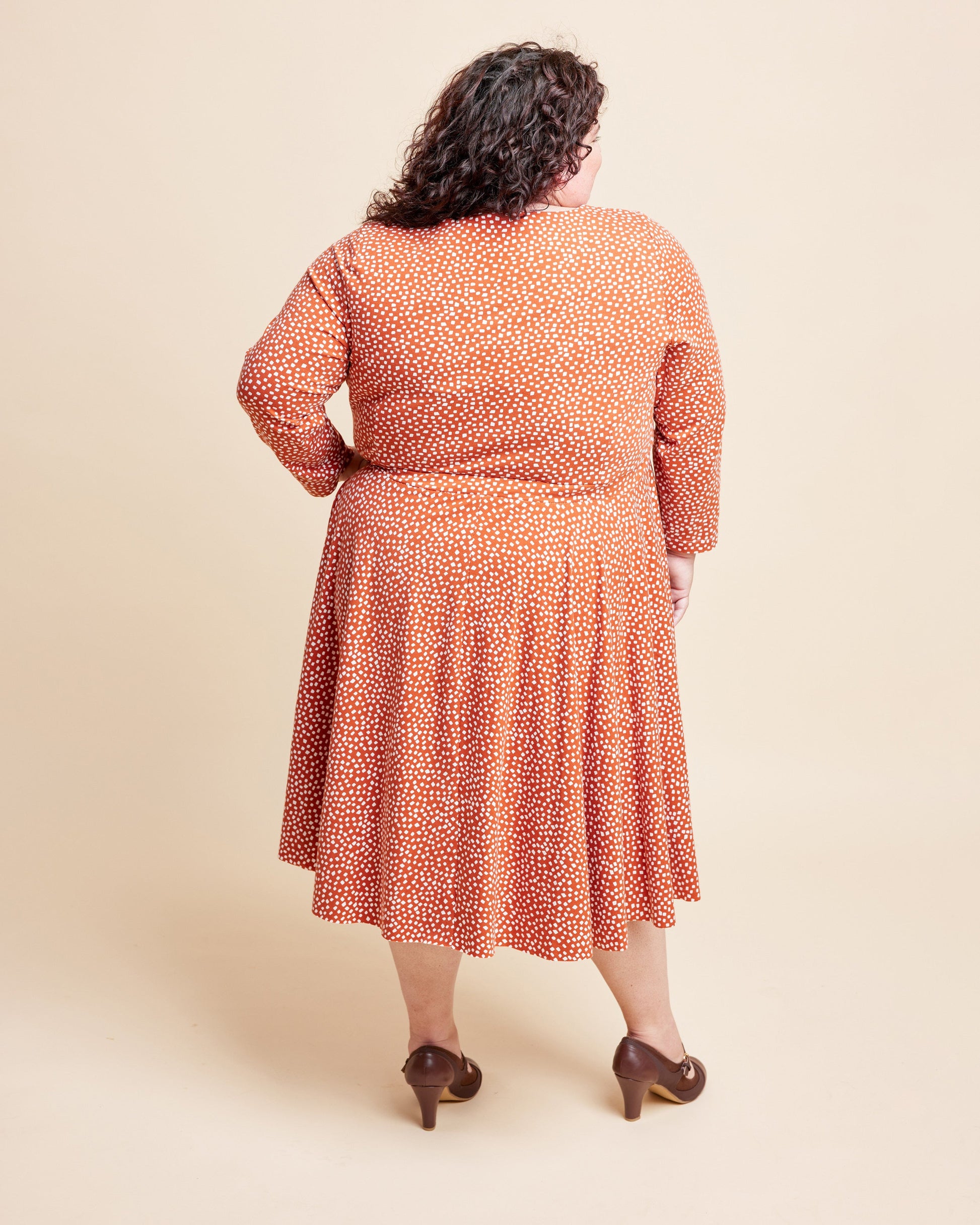Woman wearing a patterned dress on a beige background. This is the Grafton Dress, Top & Skirt sewing pattern from Cashmerette.
