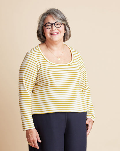 Woman wearing a yellow and white striped shirt against a beige background. This is the Grafton Dress, Top & Skirt sewing pattern from Cashmerette.