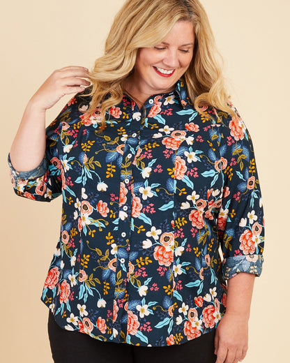 Woman wearing a floral blouse on a beige background. This button-up shirt is the Harrison Shirt sewing pattern from Cashmerette.