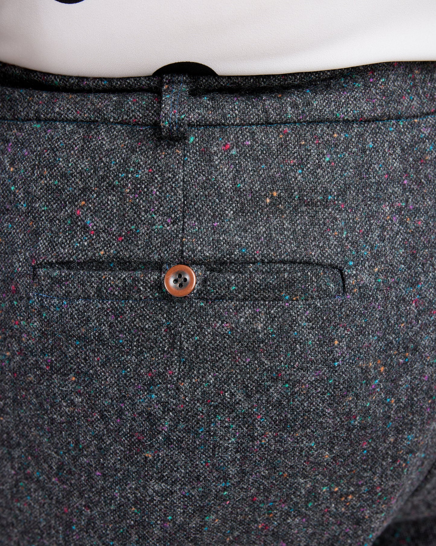 Close-up of a gray textured fabric with a button on a white background. These pants are the Meriam Trousers sewing pattern from Cashmerette.