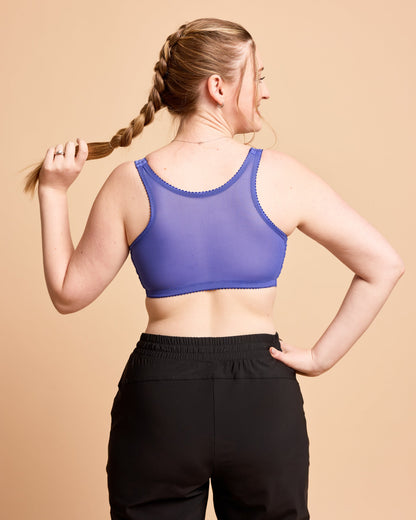 Woman wearing a purple sports bra and black leggings against a beige background. This is the Cashmerette Somerville Sports Bra sewing pattern for big boobs.