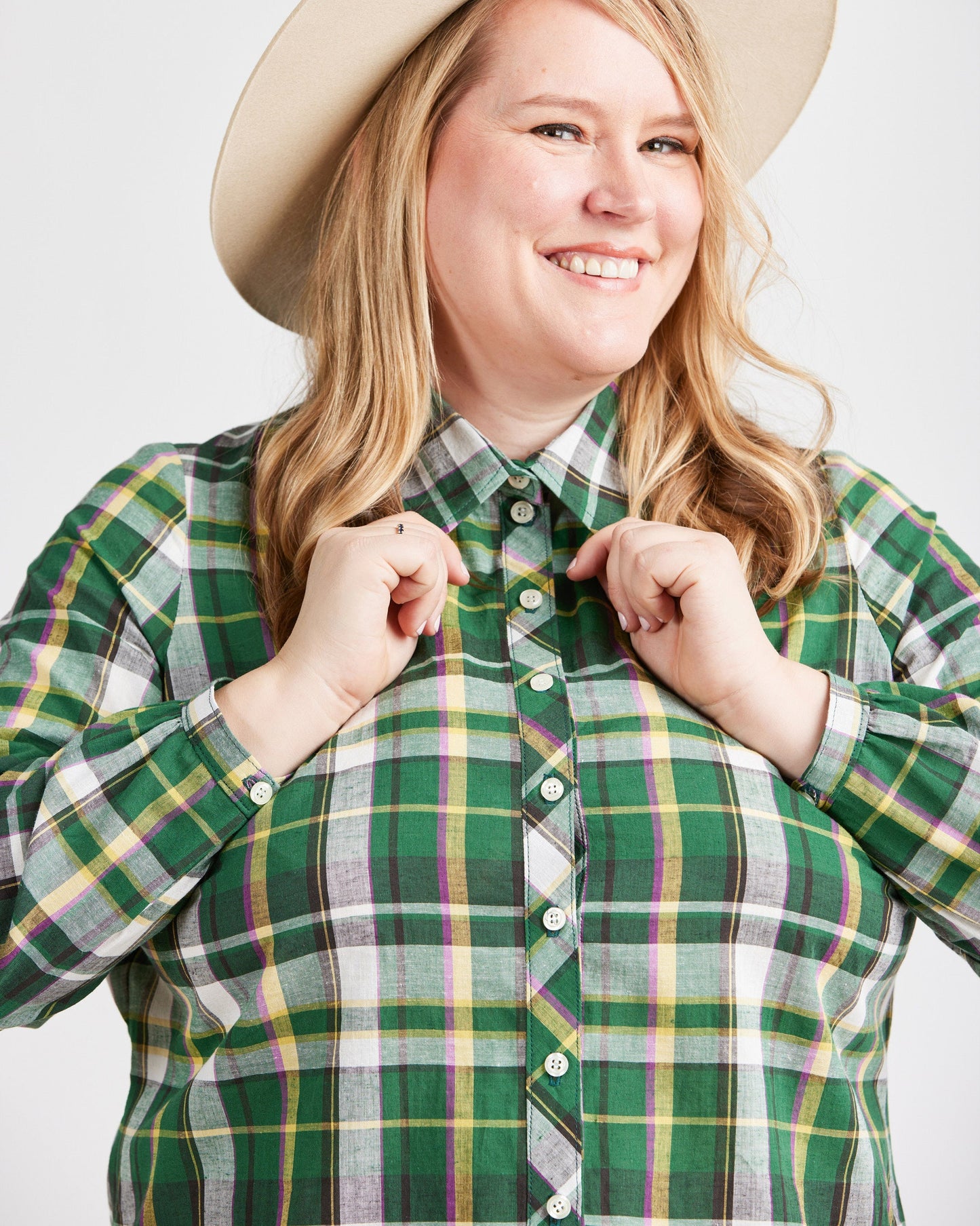 Person wearing a green plaid shirt with a beige hat on a white background. This top is the Vernon Shirt sewing pattern from Cashmerette.